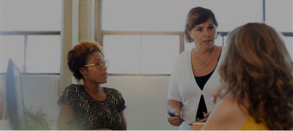 Three women in a conference room discussing ideas